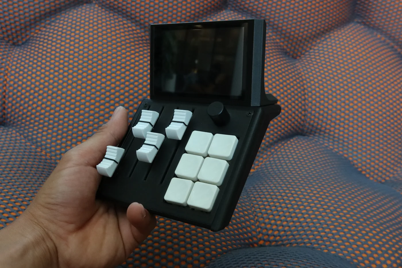 Mixlar M1X held in one hand, faders and macro keys in full view